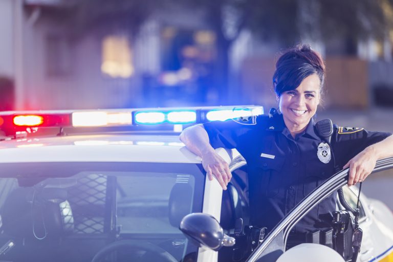 Female police officer standing next to patrol car